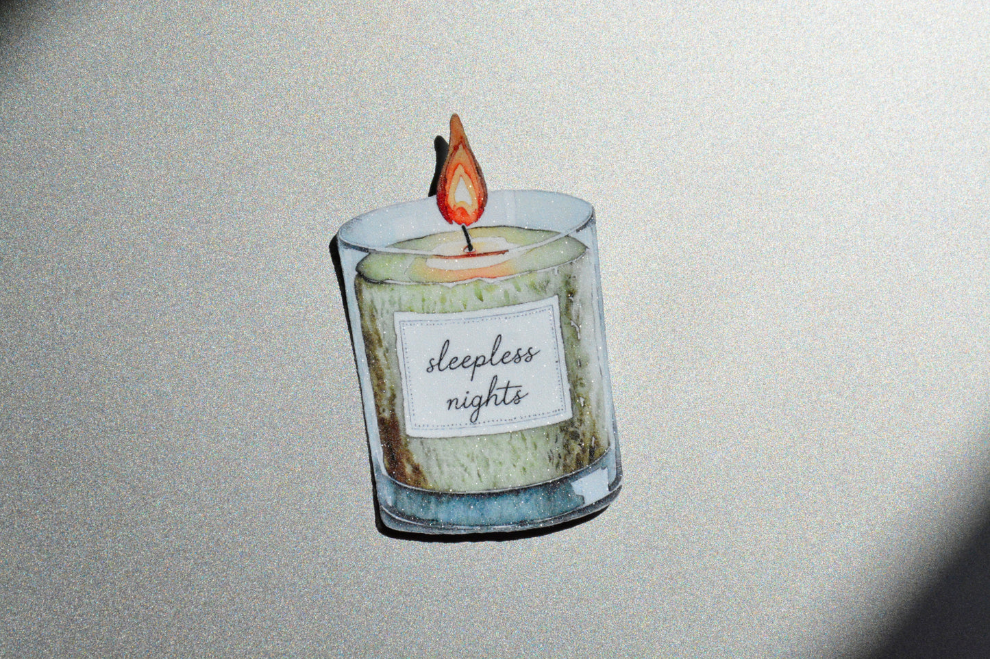 Sleepless Nights holographic watercolor candle sticker on a gold glittery surface
