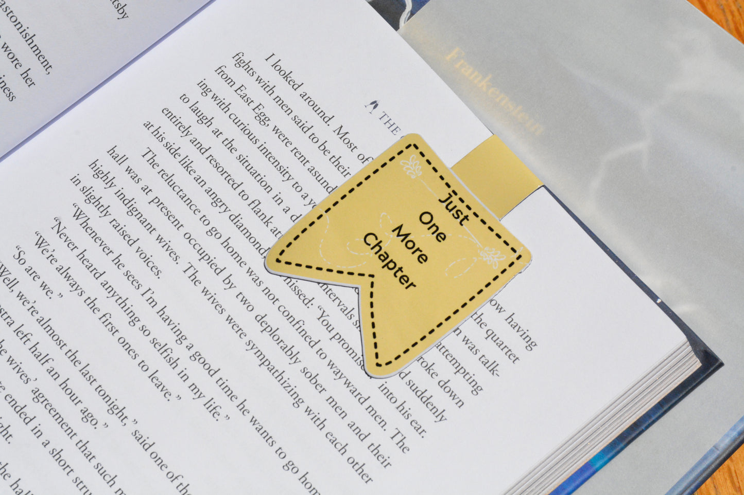 Cute magnetic bookmark featuring the phrase "Just One More Chapter," securely marking a page in a novel.