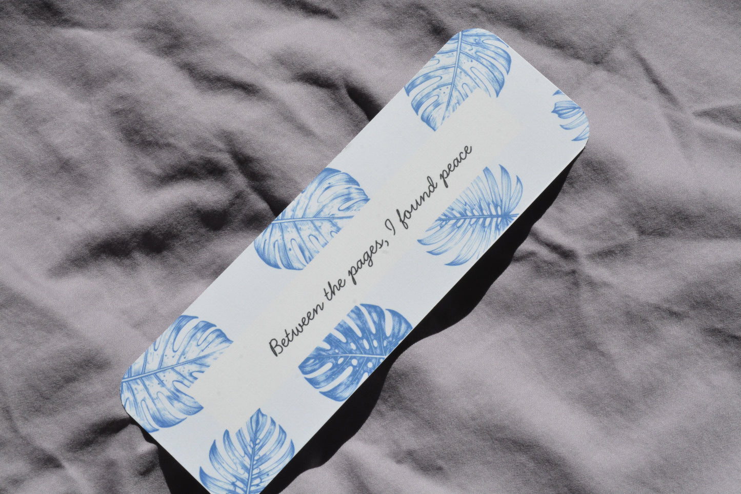 Rounded corner linen bookmark featuring the quote "Between the pages I found peace" with a cozy reading aesthetic.