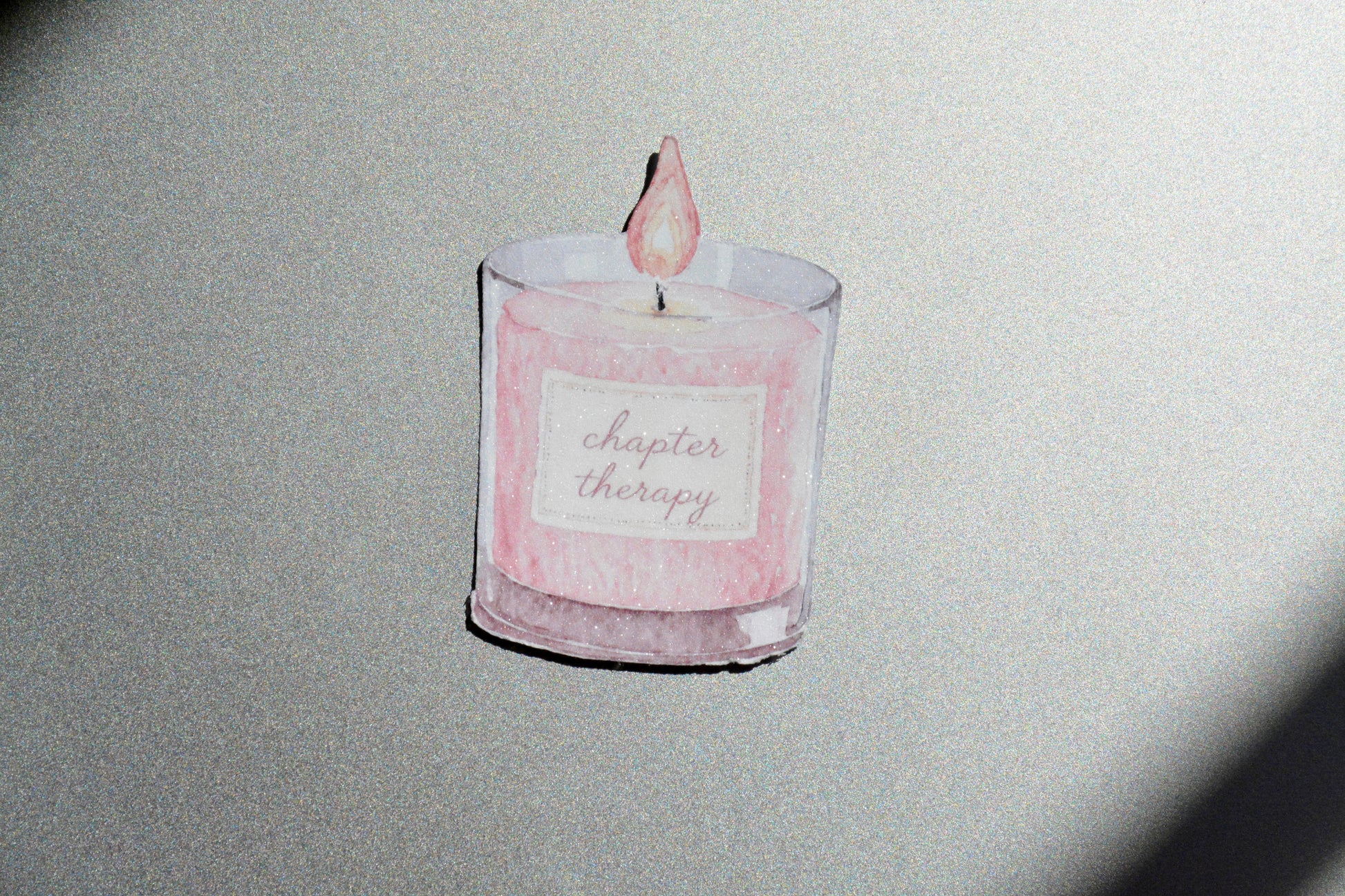 Chapter Therapy holographic watercolor candle sticker on a silver glittery surface