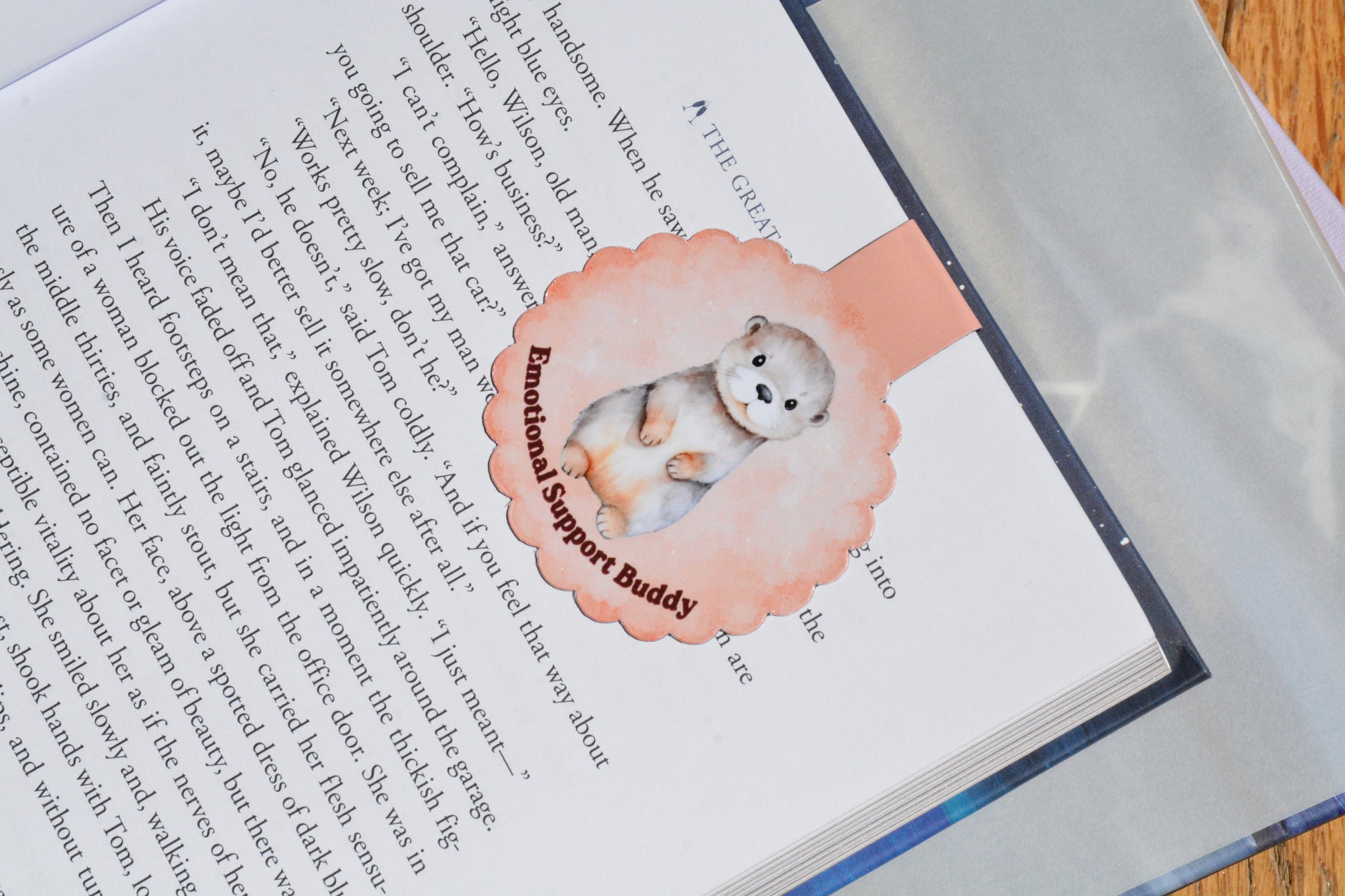Cute otter magnetic bookmark clipped inside an open book, featuring a watercolor "Emotional Support Buddy" design for book lovers and readers.