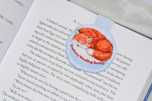 Sleeping fox magnetic bookmark clipped inside an open book, featuring a watercolor fantasy reading buddy design for book lovers.