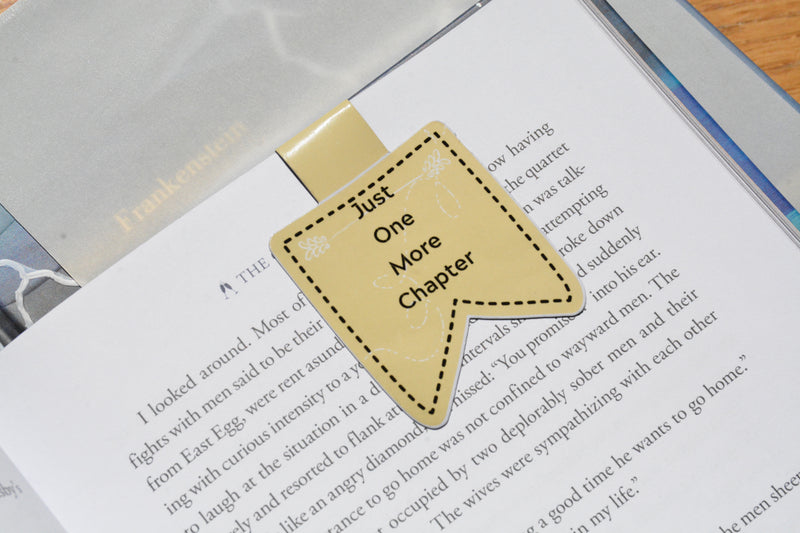 Yellow "Just One More Chapter" magnetic bookmark clipped inside an open book, handmade for book lovers.