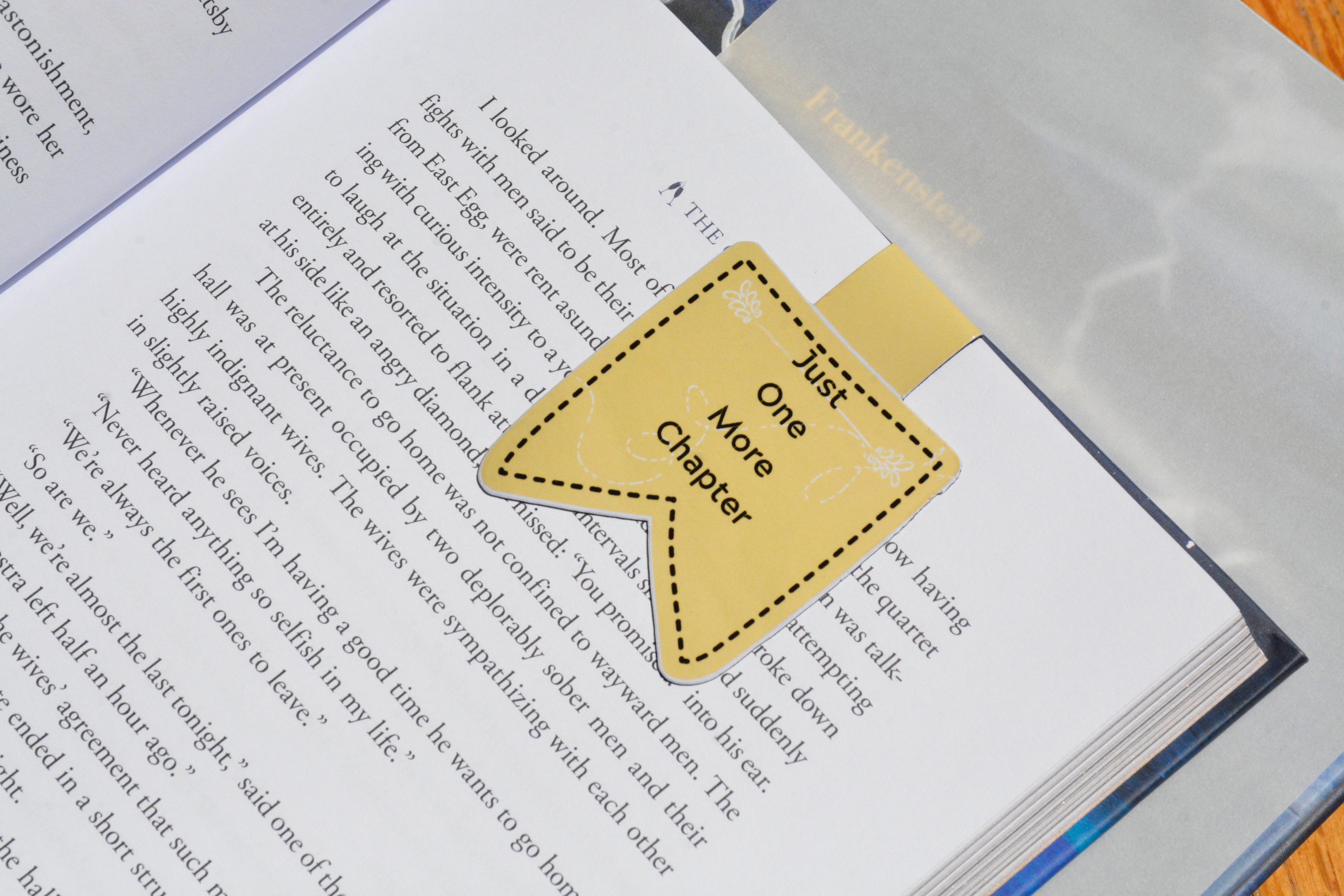 Cute magnetic bookmark featuring the phrase "Just One More Chapter," securely marking a page in a novel.