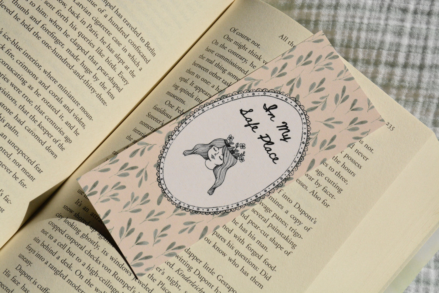 Double-sided linen bookmark featuring a delicate botanical pattern and the quote "In My Safe Place" resting inside an open book.