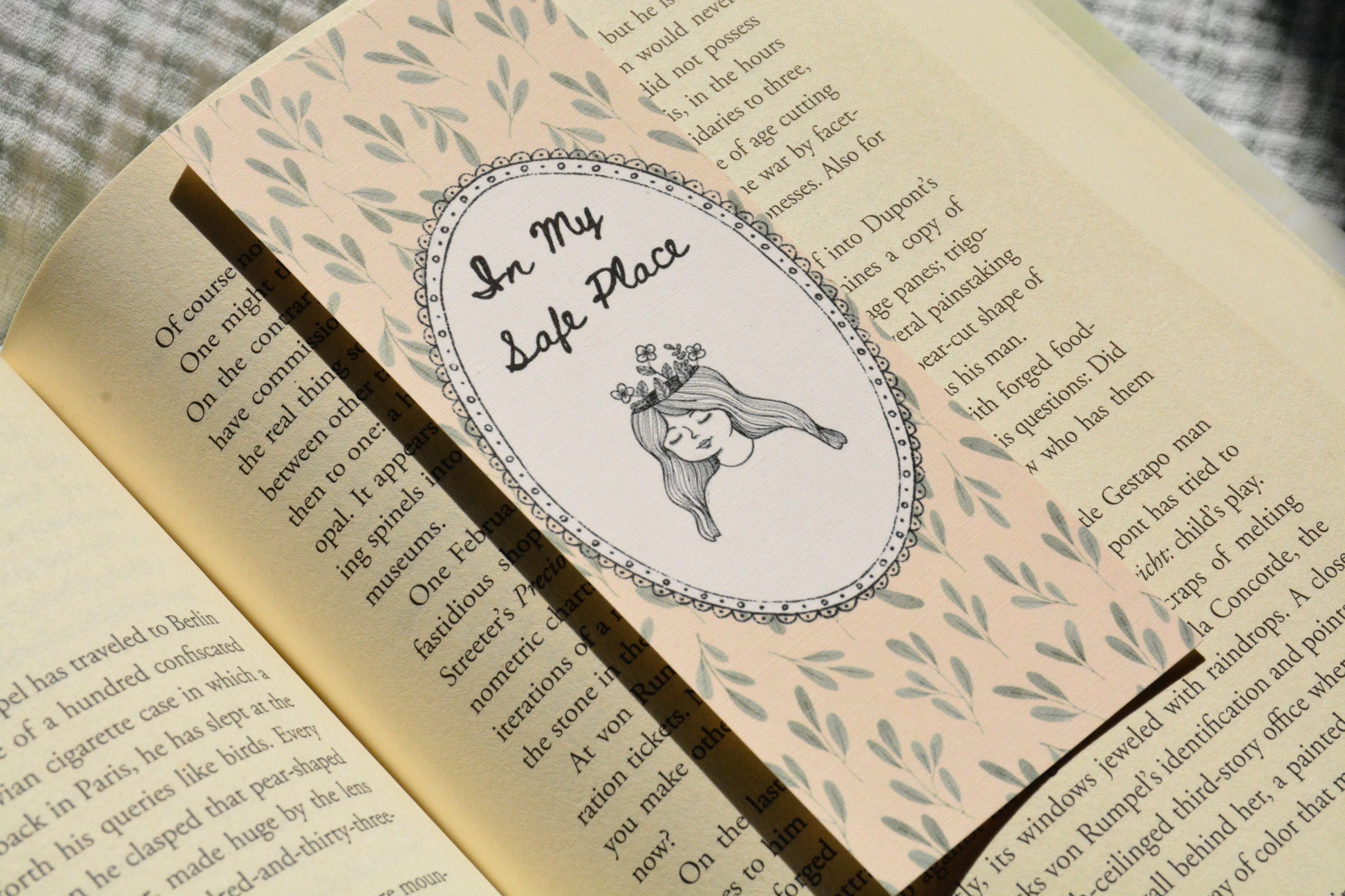 Handcrafted floral linen bookmark with a soft blush background and elegant illustration for book lovers.
