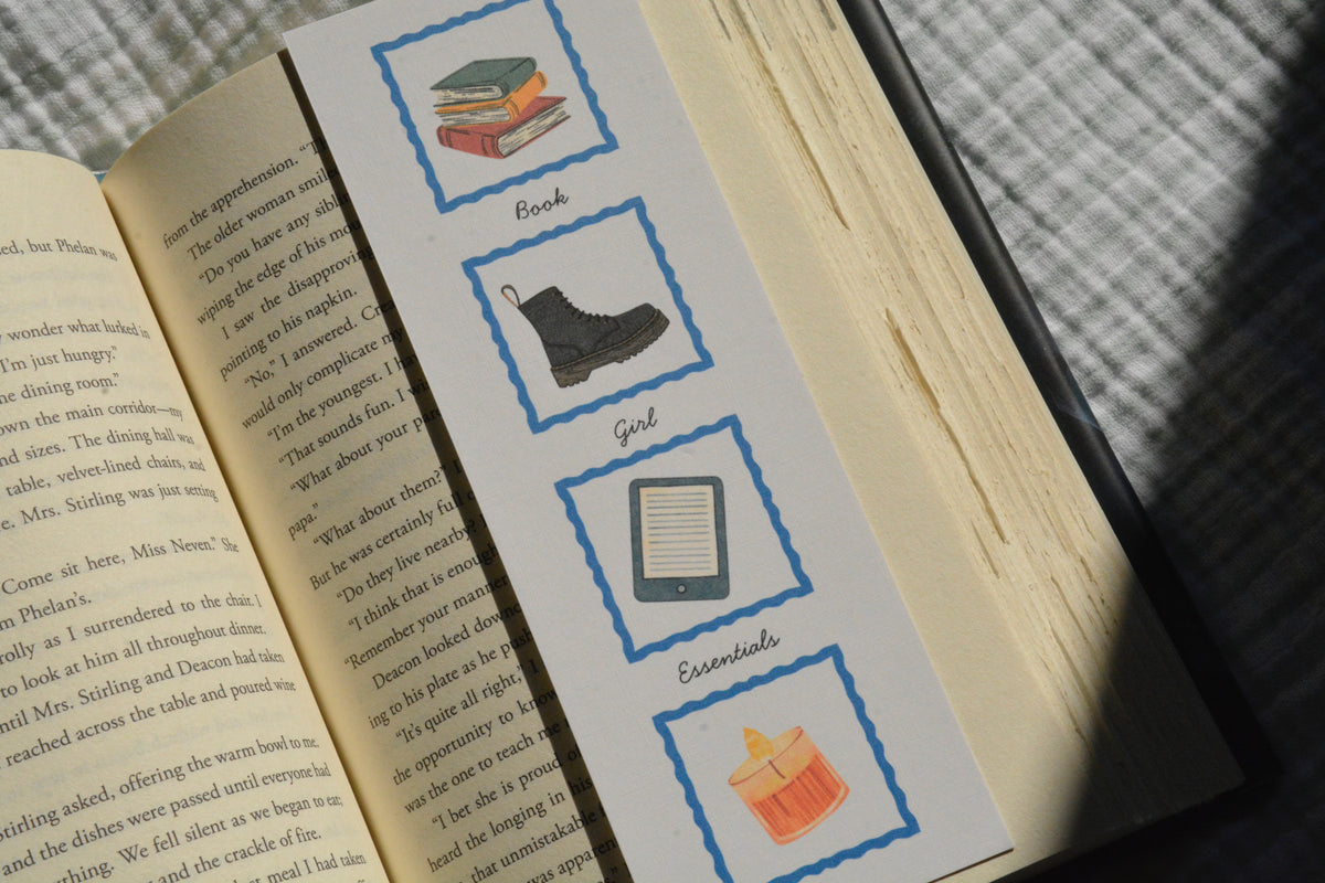 Book Girl Essentials linen bookmark with illustrations of books, a sweater, tote bag, library card, Kindle, boots, and a candle.
