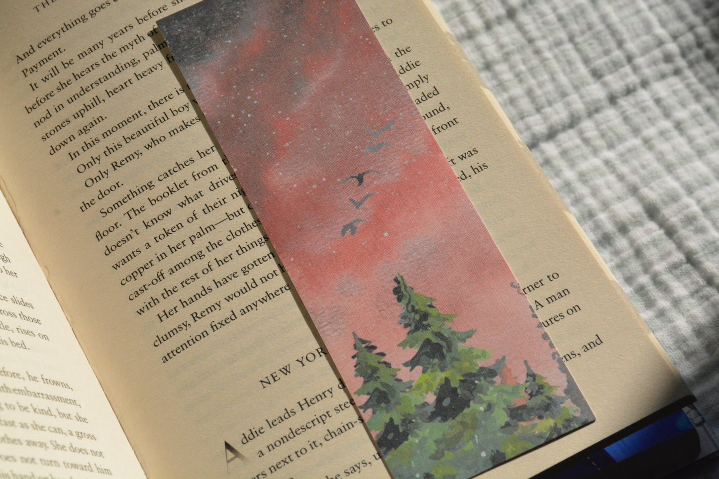 Handcrafted nature-inspired linen bookmark with peaceful day and night forest artwork tucked inside an open book.