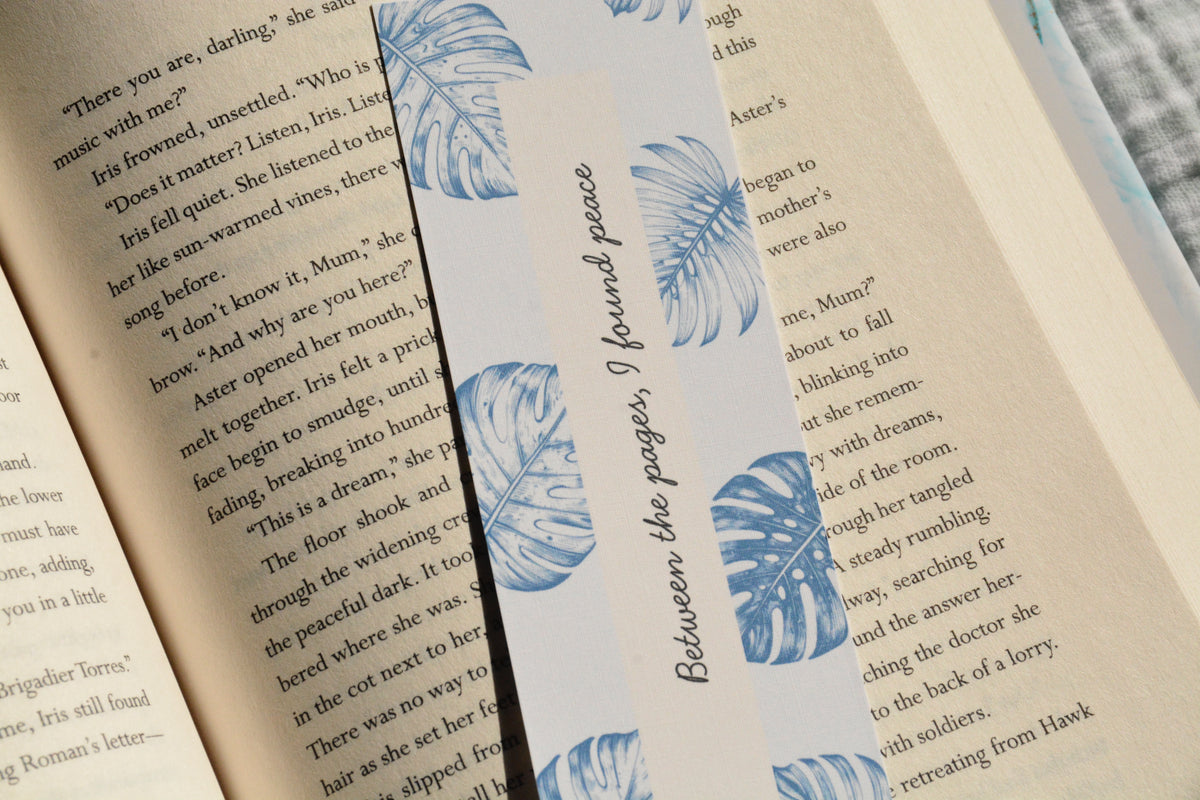 Minimalist linen bookmark with soft blue tropical leaves and a peaceful bookish quote for readers.