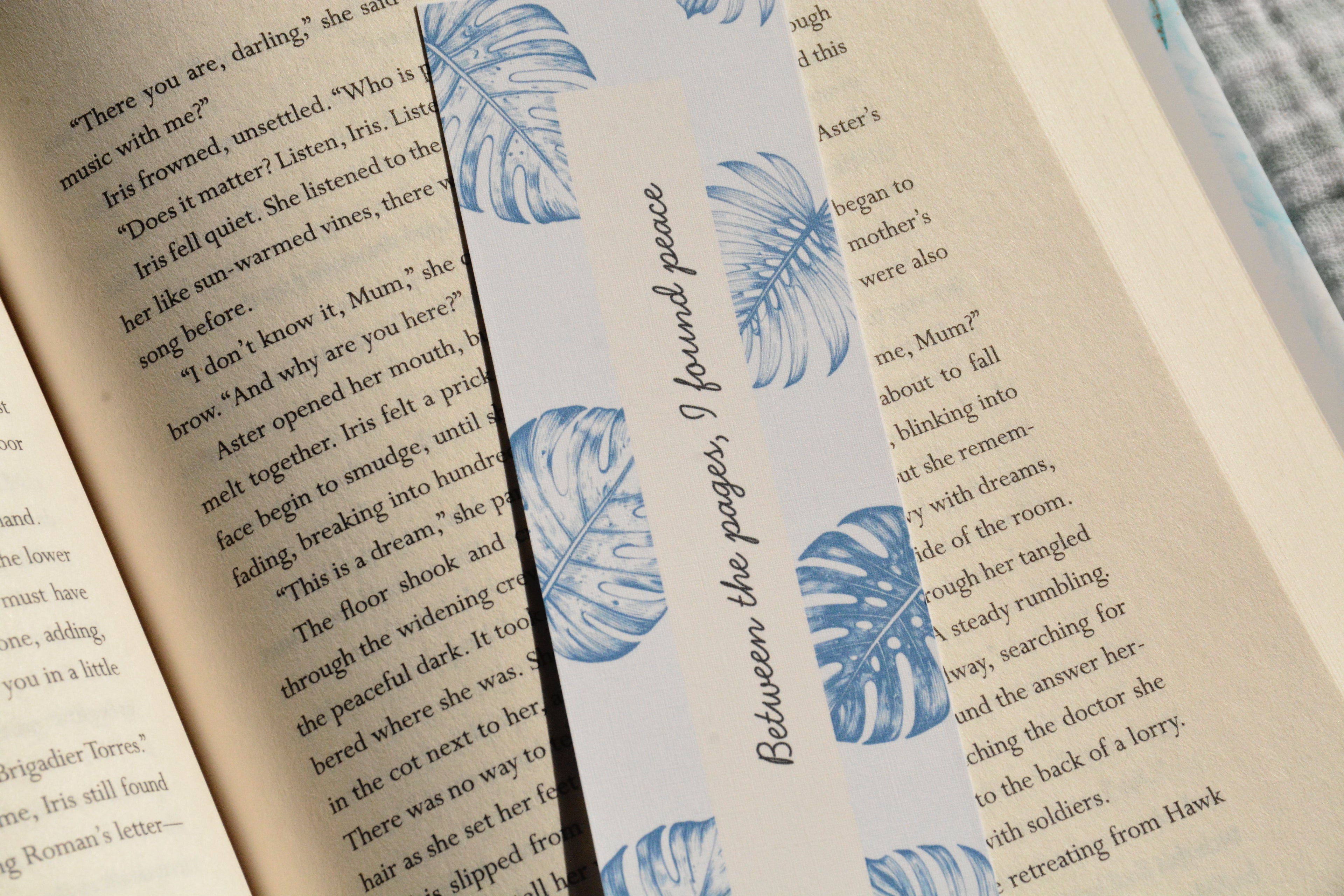 Minimalist linen bookmark with soft blue tropical leaves and a peaceful bookish quote for readers.