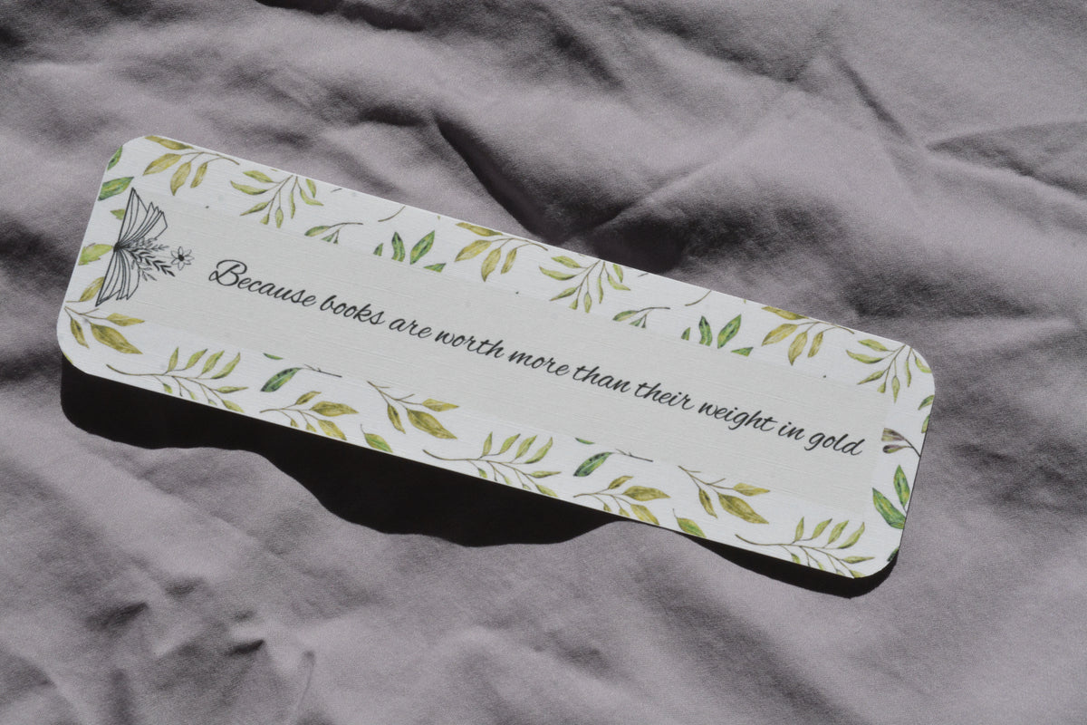 Rounded corner linen bookmark with watercolor leaves and the quote "Because books are worth more than their weight in gold" inside an open book.