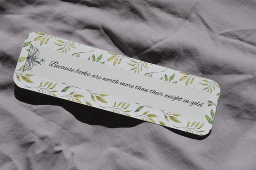 Rounded corner linen bookmark with watercolor leaves and the quote "Because books are worth more than their weight in gold" inside an open book.