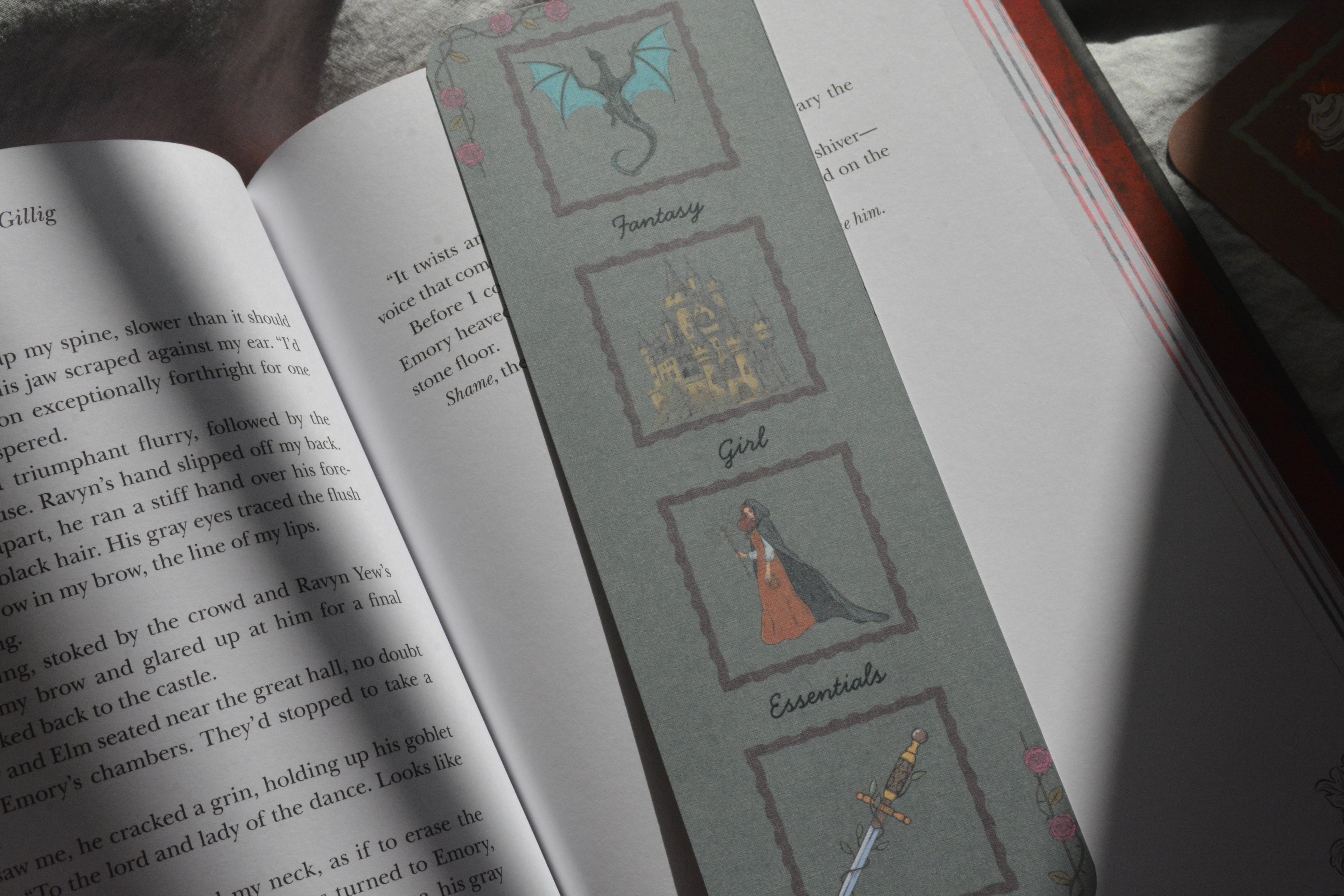 An open book spread showing printed text on the left page and a decorative page on the right with illustrated categories labeled Fantasy, Girl, and Essentials, plus small fantasy-themed drawings.
