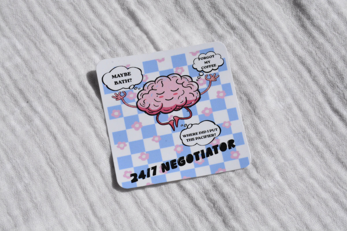 A square white coaster with rounded corners, featuring a pink cartoon brain character on a light blue and white checkered background. Speech bubbles around the brain read 'MAYBE BATH?', 'WHEN MY COFFEE DIES', and 'WHERE DID I PUT THE BRAINS?', with '24/7 NEGOTIATOR' printed at the bottom.