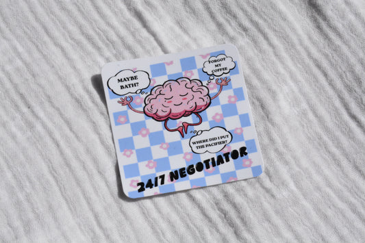 A square white coaster with rounded corners, featuring a pink cartoon brain character on a light blue and white checkered background. Speech bubbles around the brain read 'MAYBE BATH?', 'WHEN MY COFFEE DIES', and 'WHERE DID I PUT THE BRAINS?', with '24/7 NEGOTIATOR' printed at the bottom.