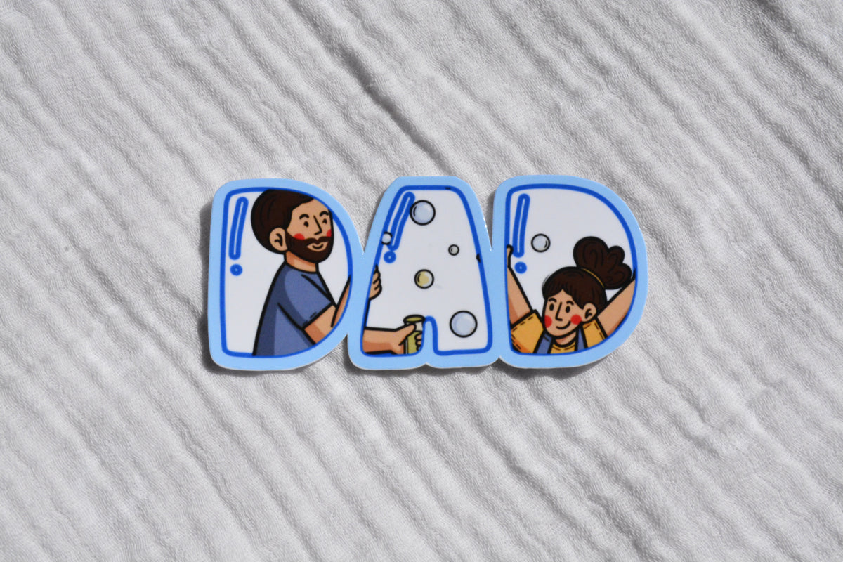A set of three die-cut stickers spelling 'DAD' in blue-outlined letters, featuring cartoon illustrations of a father washing a car and a daughter washing bubbles, placed on a textured white fabric background.