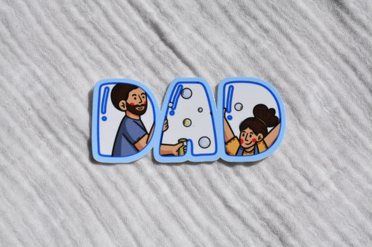 A set of three die-cut stickers spelling 'DAD' in blue-outlined letters, featuring cartoon illustrations of a father washing a car and a daughter washing bubbles, placed on a textured white fabric background.