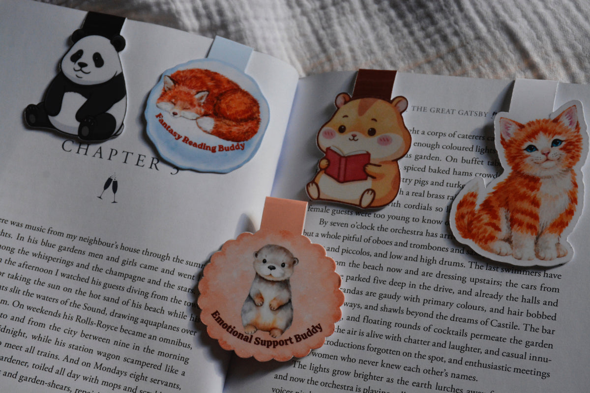 A set of magnetic bookmarks feating fox, panda, hamster, kitten and otter. Bundle set on a book