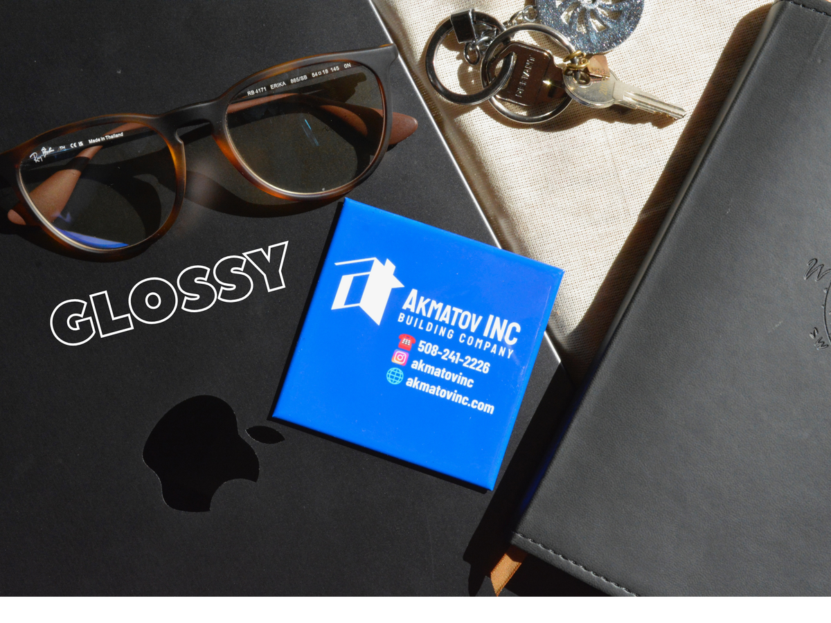 Blue  Glossy business magnets with Akmatov Inc logo on a black surface with sunglasses and keys.