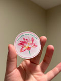 Handmade glitter affirmation sticker featuring a watercolor pink lotus flower with the quote "I am healthy, strong, and full of life," displayed in hand.