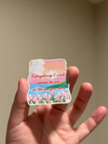 Handmade glitter affirmation sticker featuring a watercolor tulip landscape and the quote "Everything I need comes to me at the perfect time," displayed in hand for Kindles, journals, laptops, and water bottles.