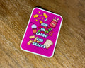 A rectangular pink sticker with rounded corners featuring a cartoon snack illustration and the text 'I RUN ON CARBS AND SNACKS' in white, placed on a brown wooden surface.