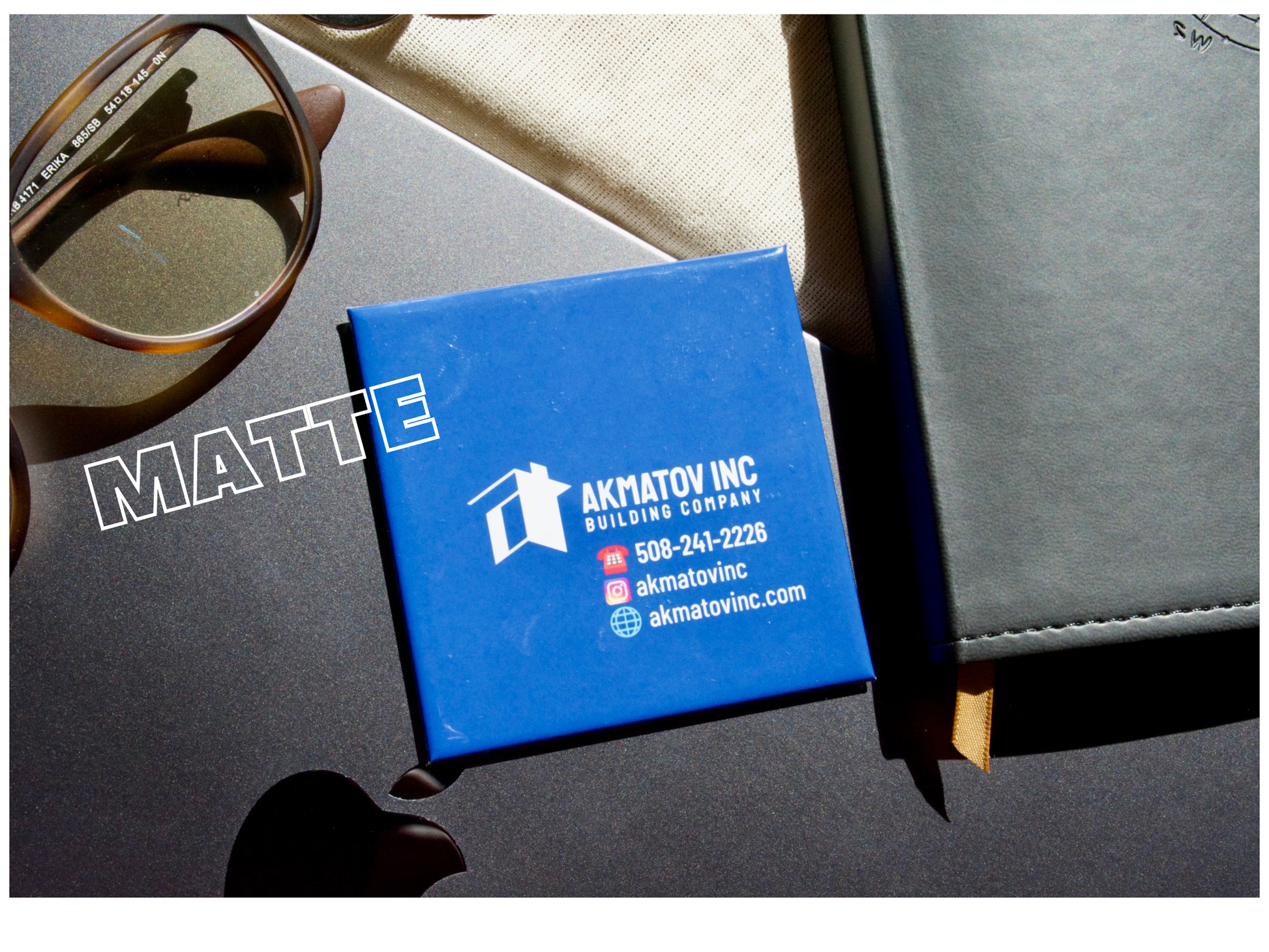 Blue business magnets with Akmatov Inc branding on a reflective surface