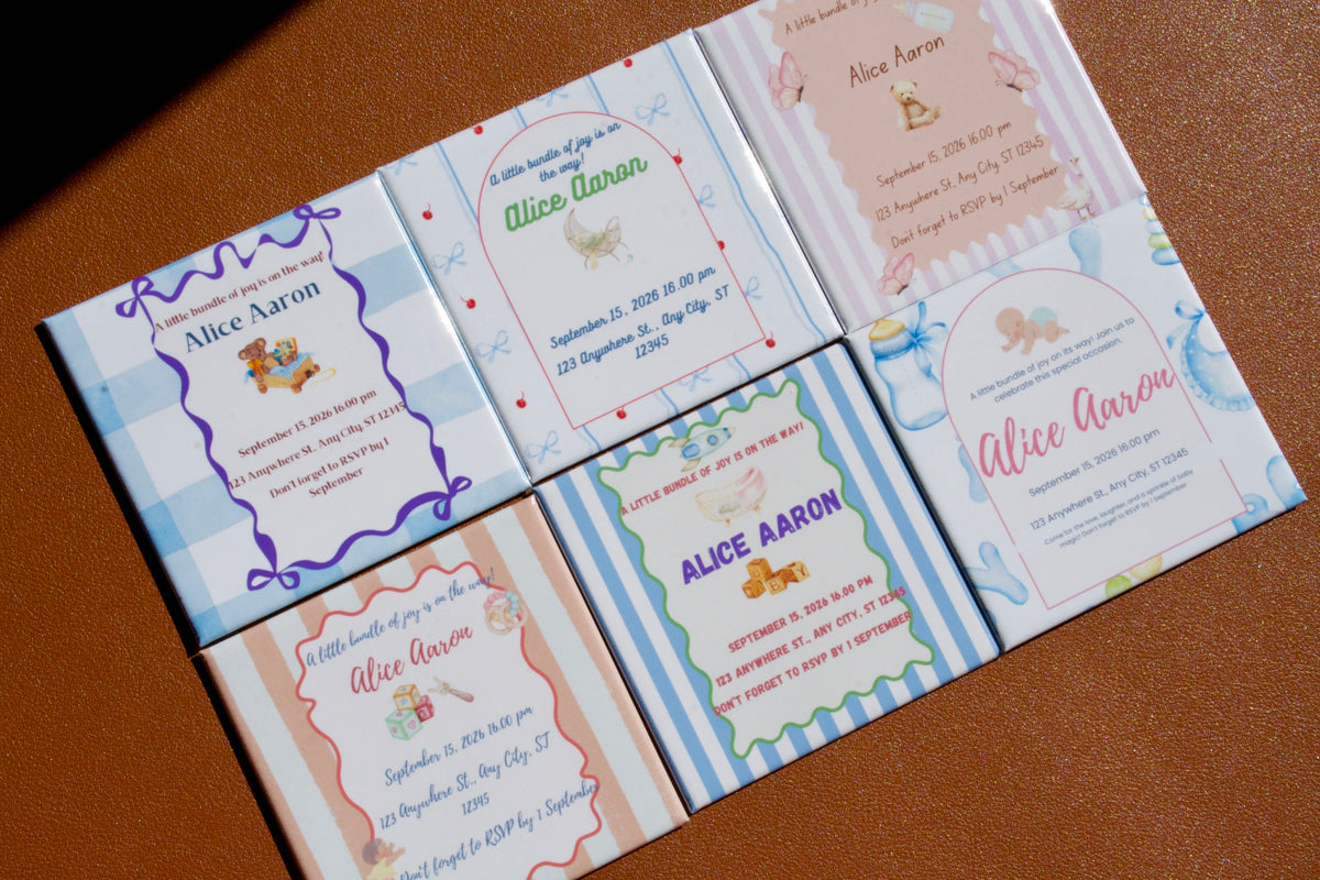 Set of baby shower invitations with colorful designs on a brown surface