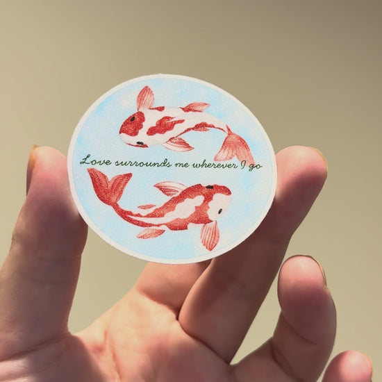 Close-up video of a watercolor koi fish affirmation sticker with glitter laminate, showcasing its sparkling finish, calming artwork, and handmade details from multiple angles.