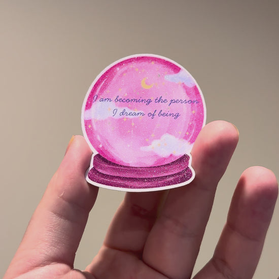 The video showcasting pink crystal ball glitter affirmation sticker with the quote "I am becoming the person I dream of being."