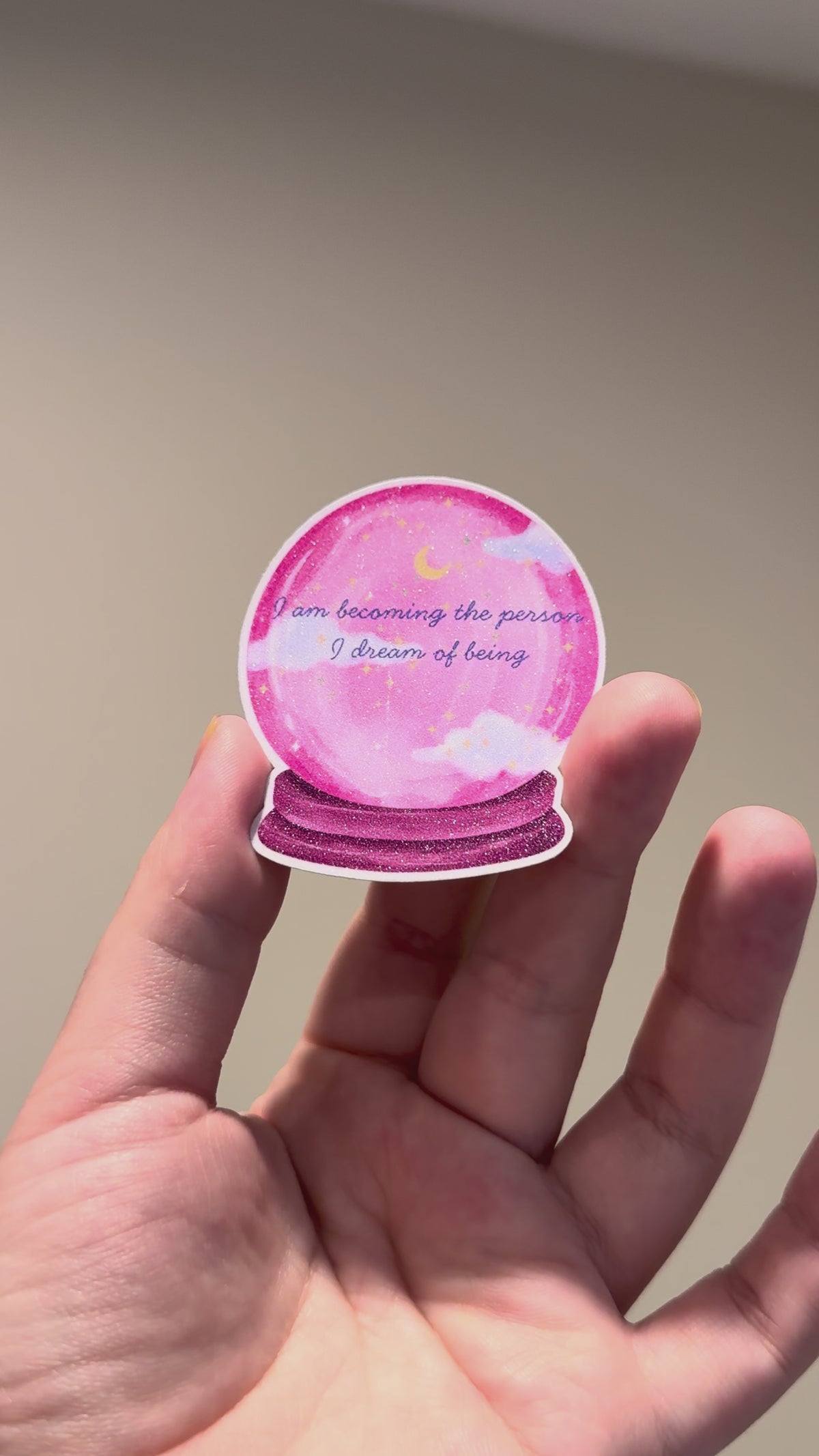 The video showcasting pink crystal ball glitter affirmation sticker with the quote "I am becoming the person I dream of being."