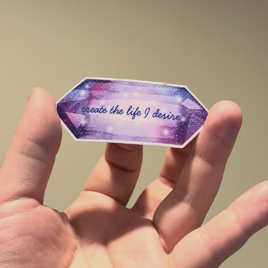 Close-up video of a purple crystal-inspired affirmation sticker with glitter laminate, highlighting its sparkling finish and premium handmade quality from different angles.