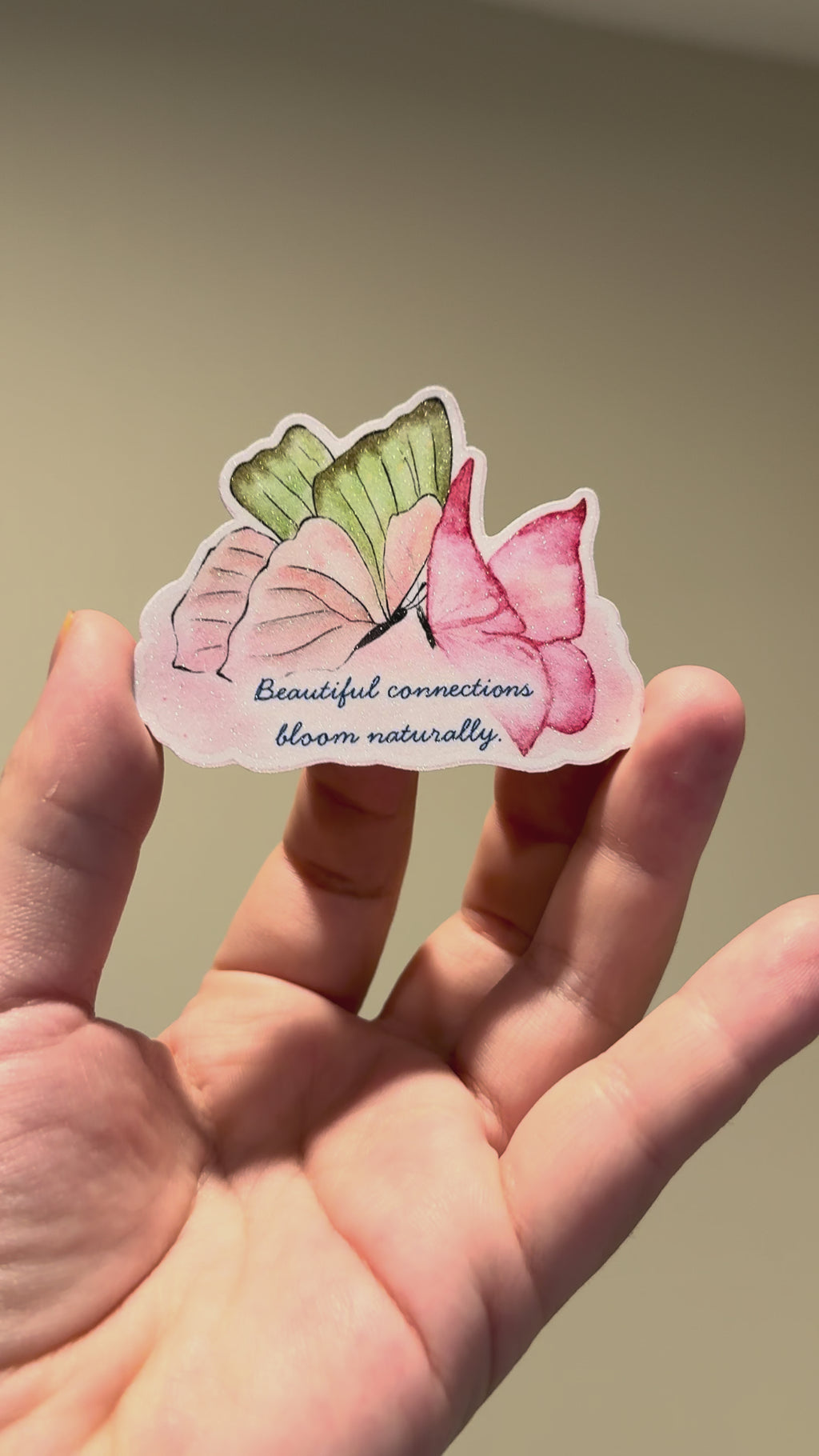 Close-up video of a watercolor butterfly affirmation sticker with glitter laminate, showcasing its sparkling finish and handmade details from different angles.