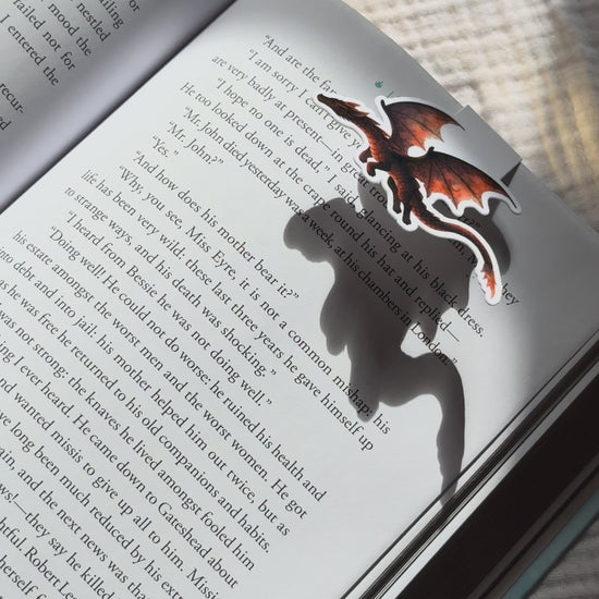 Dragon magnetic bookmark demo: cute fantasy dragon design clips securely onto book pages with strong magnetic closure, shown on pink Keepsake House backing card